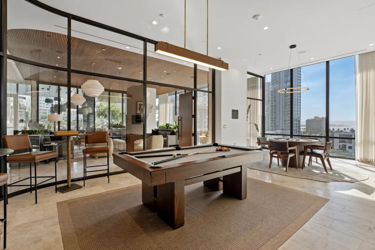 Billiards room with pool table, card table, bar seating, and floor-to-ceiling windows.