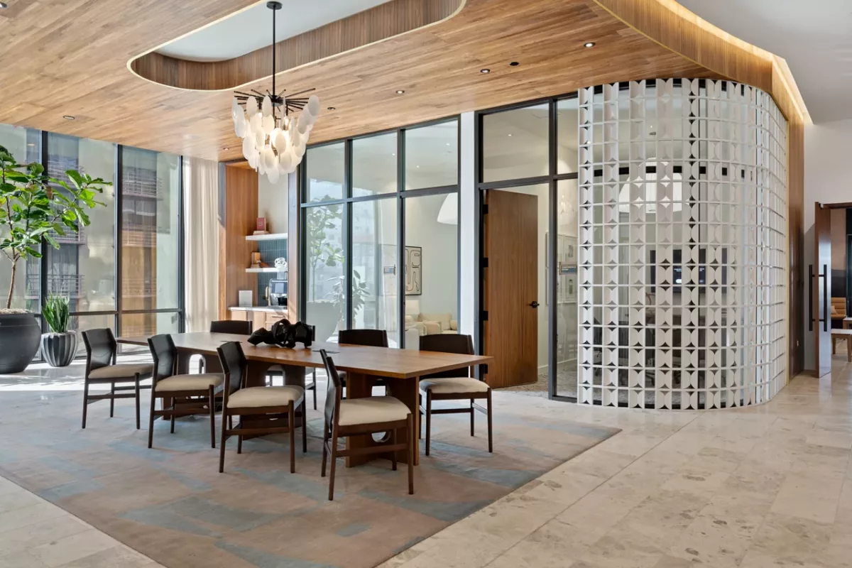 Modern clubroom with wood ceiling, dining table, glass walls, and decorative partition.