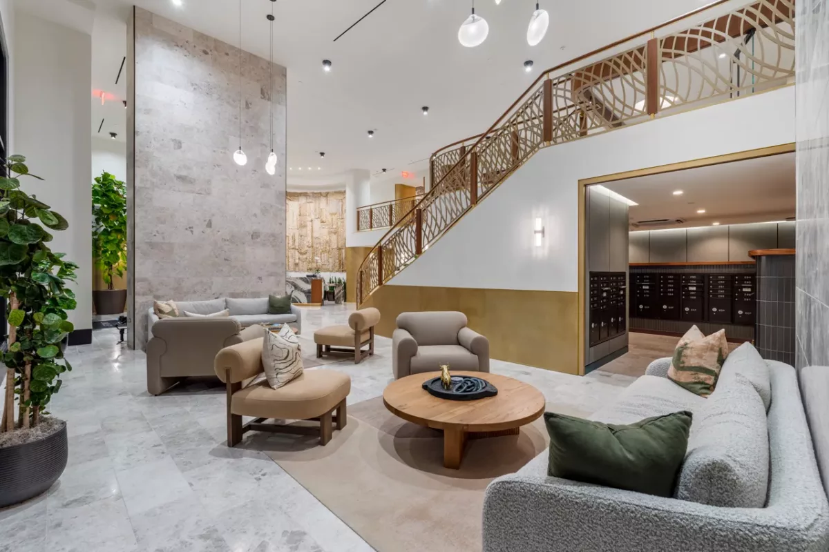 Lobby with modern seating, curved staircase, wall sconces, and visible mailroom area.