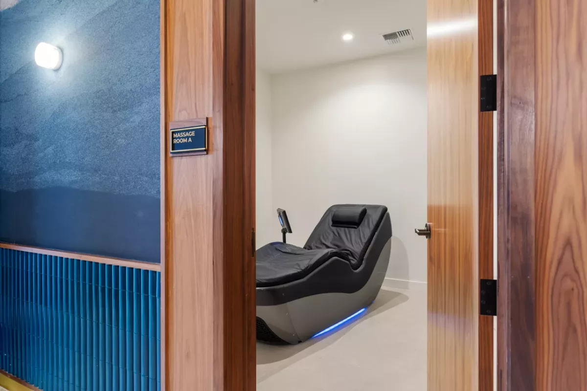 Massage room with modern black recliner chair and minimal decor.