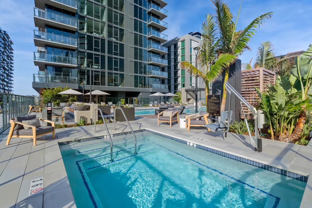 Rooftop spa with lounge chairs, palm trees, and modern high-rise building backdrop.