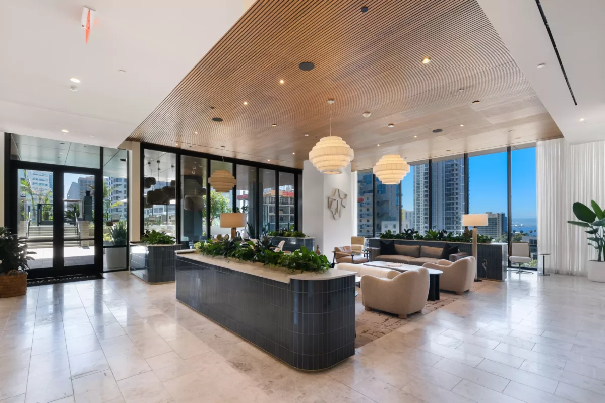 Spacious clubroom with reception desk, lounge seating, and floor-to-ceiling windows.