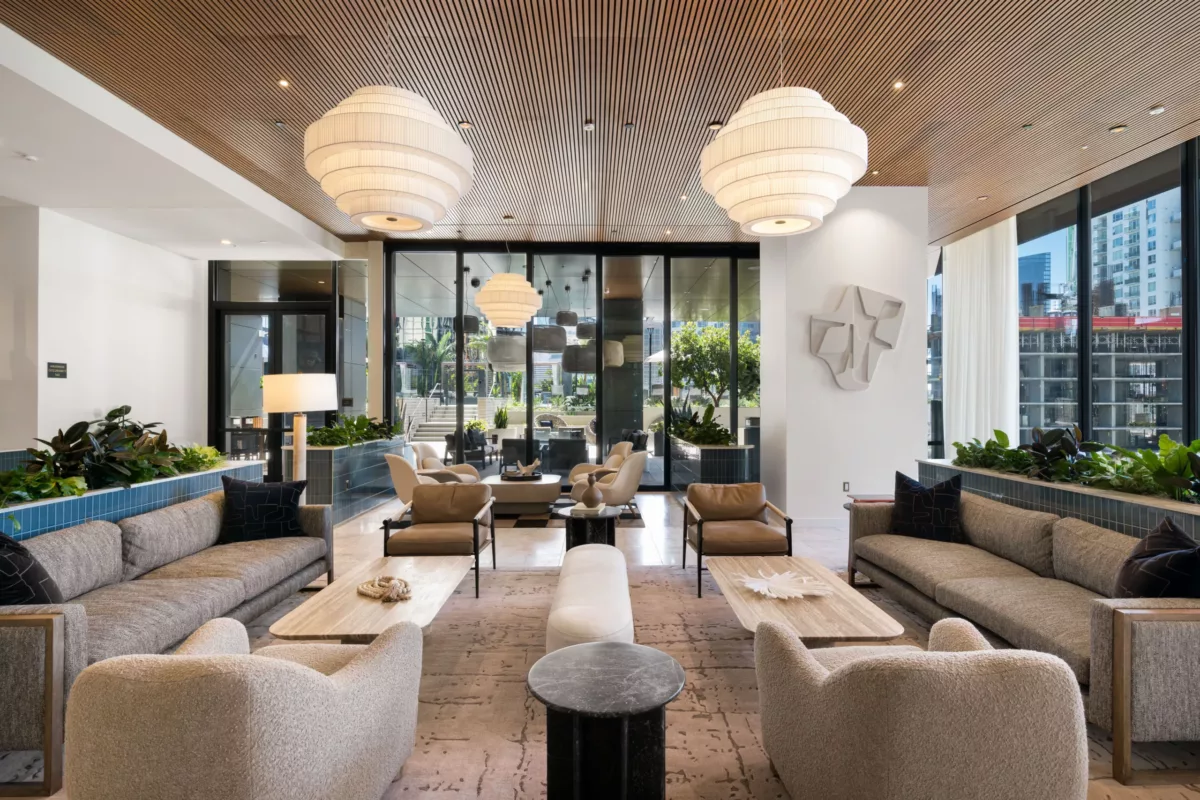 Clubroom lounge with layered chandeliers, modern sofas, and glass wall views.