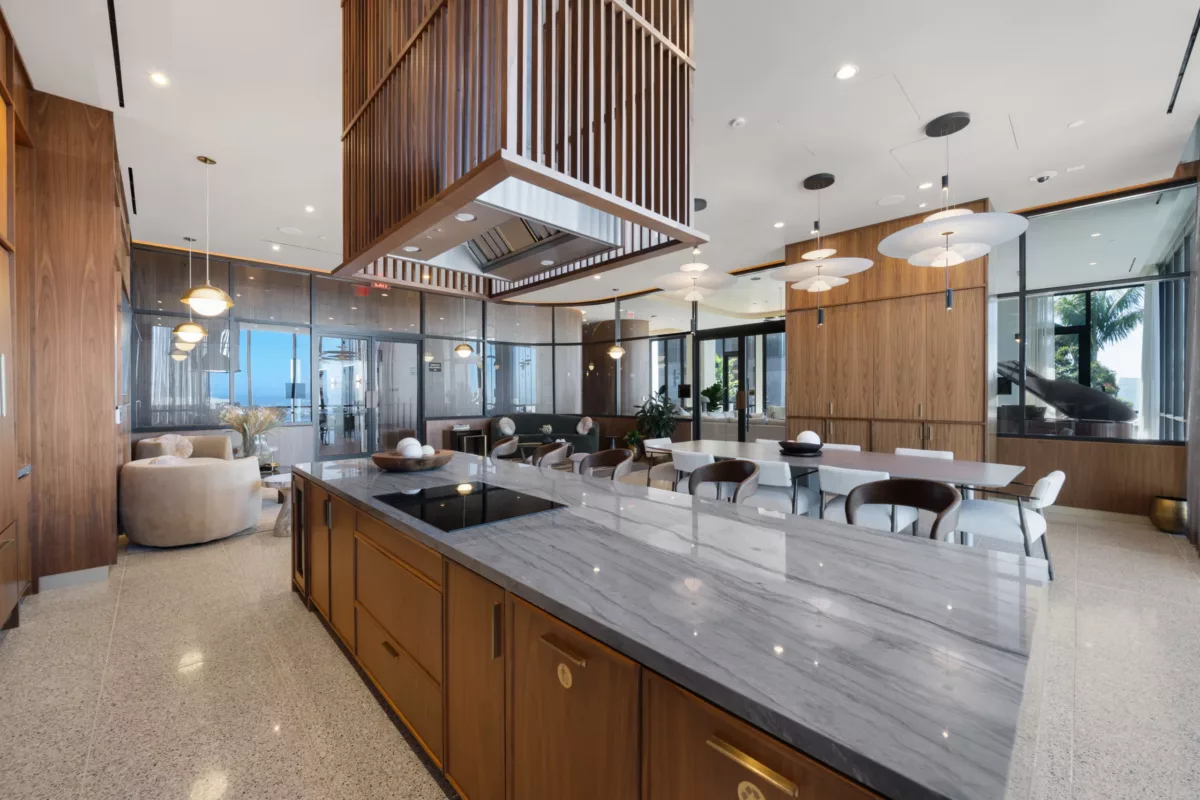 Modern demonstration kitchen with marble island, wood finishes, and stylish pendant lighting.
