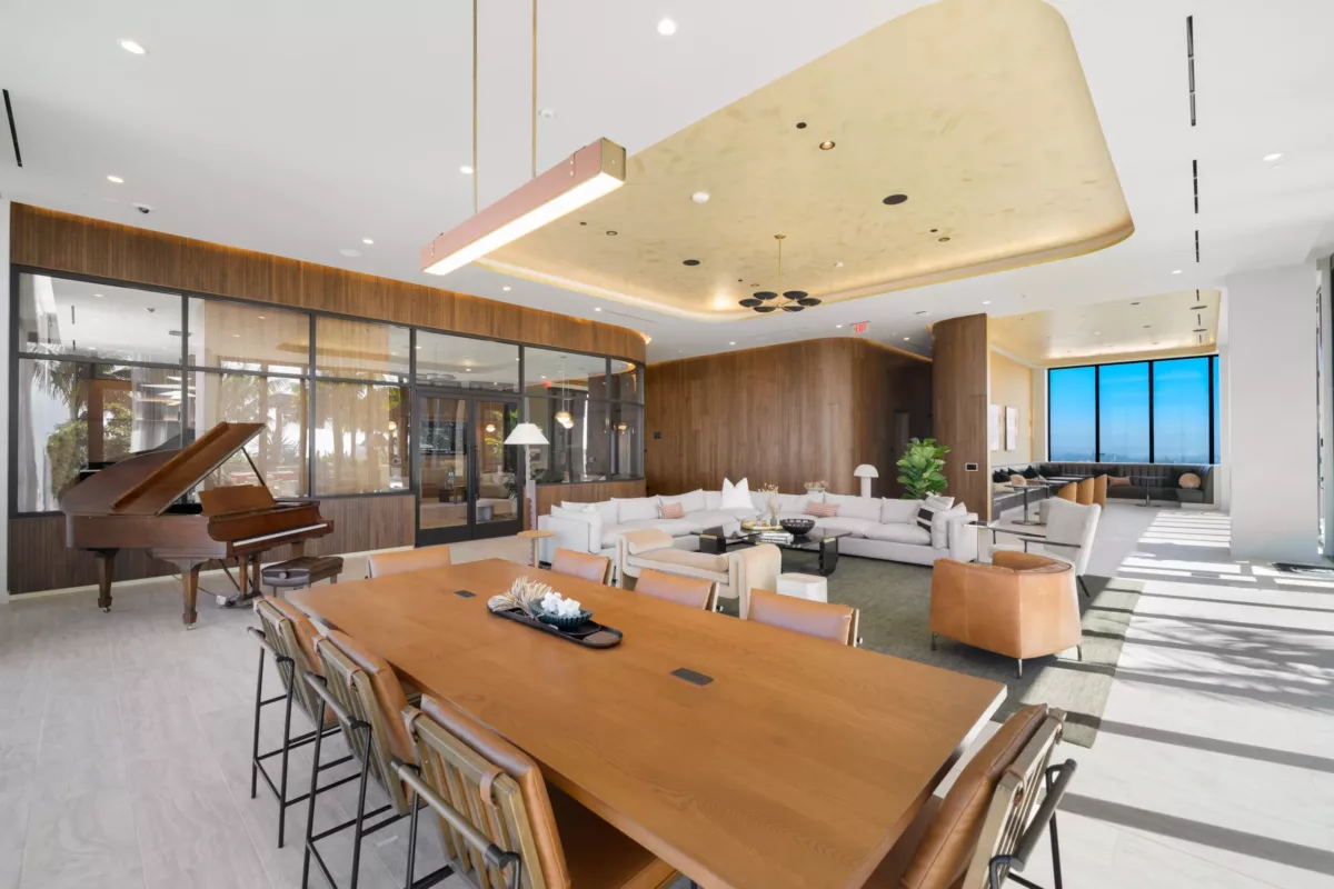 Sky lounge with grand piano, long dining table, and modern sectional seating.