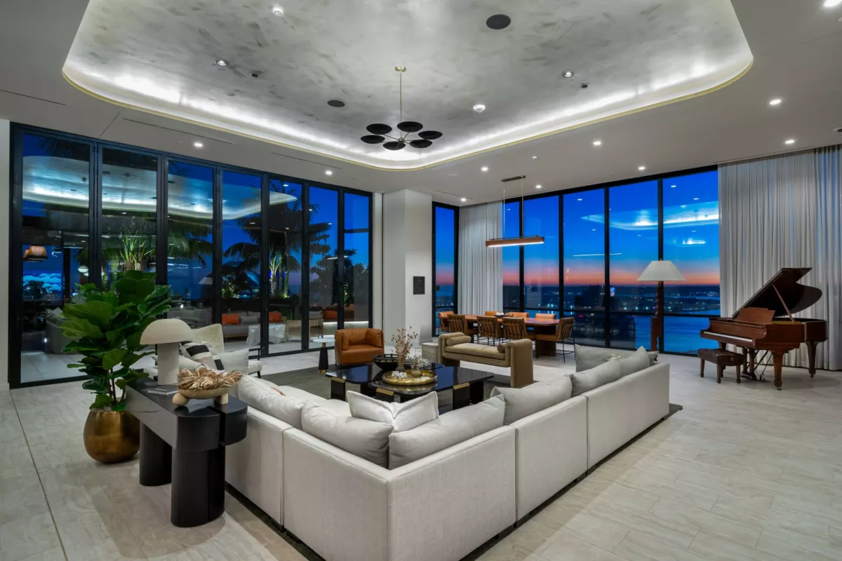 Sky lounge at dusk with large sectional sofa, piano, and panoramic city views.