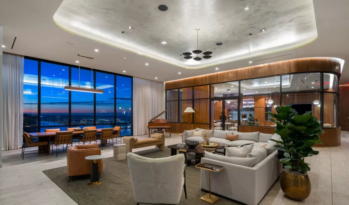 Elegant sky lounge at dusk with city view, cozy seating, grand piano, and modern lighting.