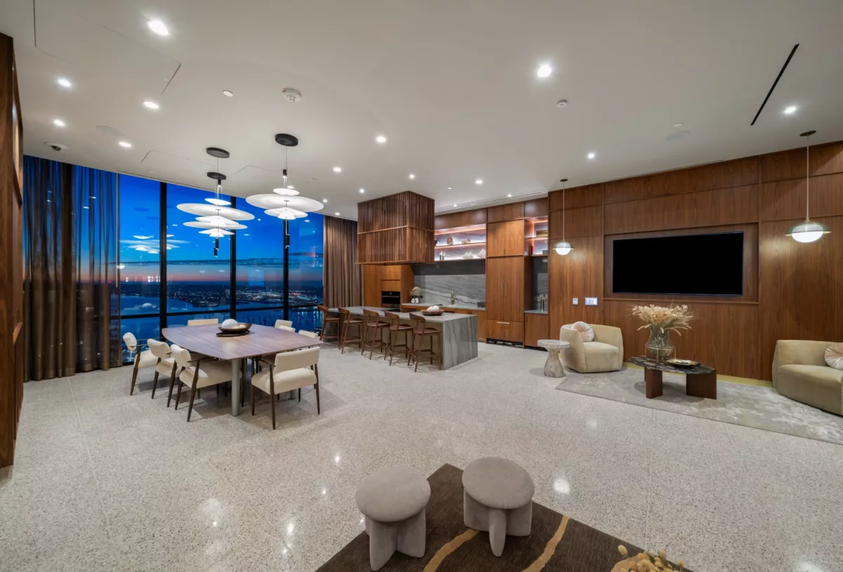Sky lounge at dusk with dining table, marble kitchen island, and panoramic city views.