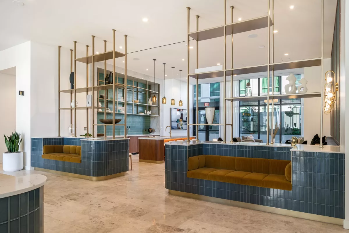 Chic lounge with built-in blue and orange sofas and decorative gold metal dividers separating it from a kitchen and bar.