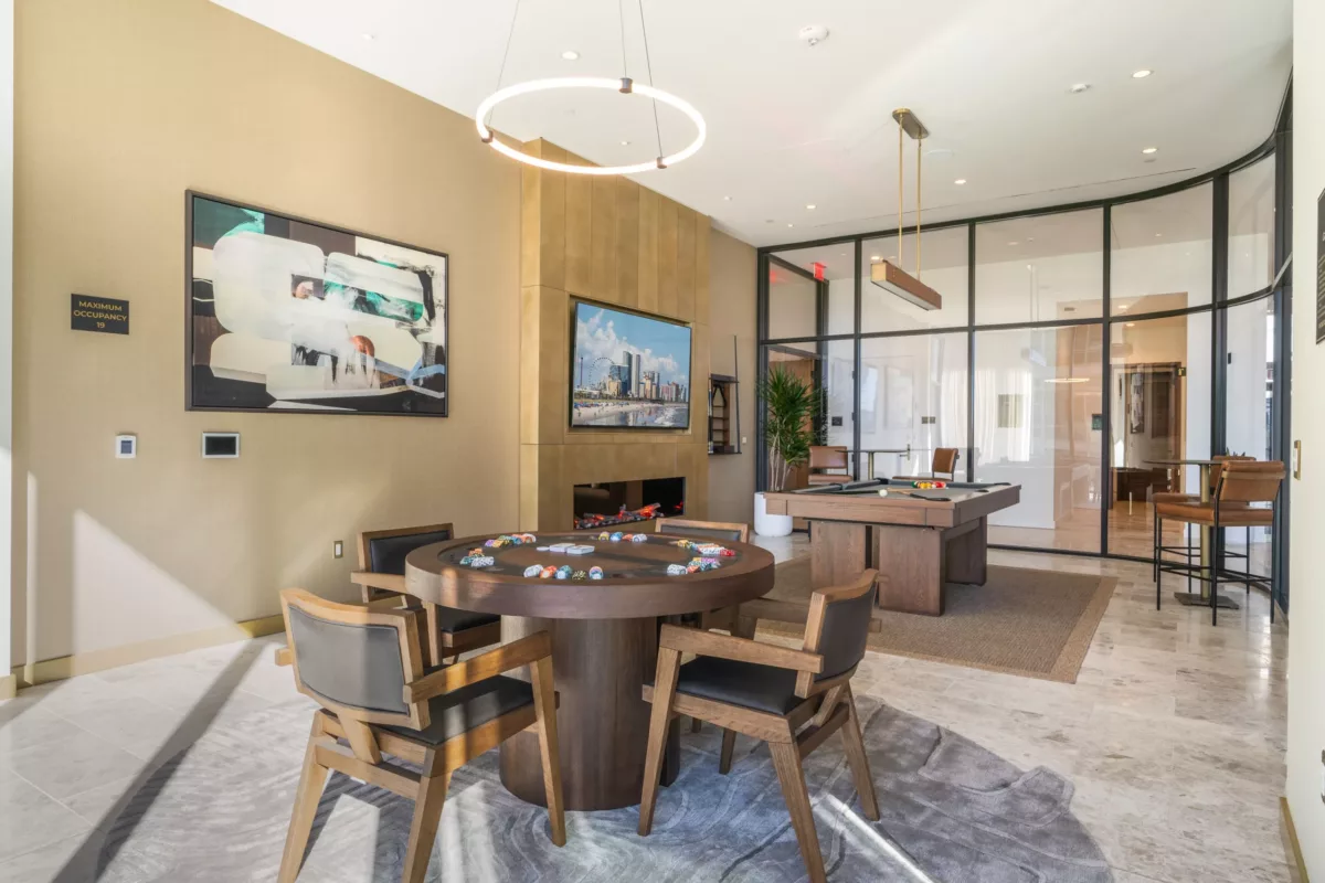 Game room with a poker table, a pool table, art pieces, and glass walls separating it from the adjacent areas.