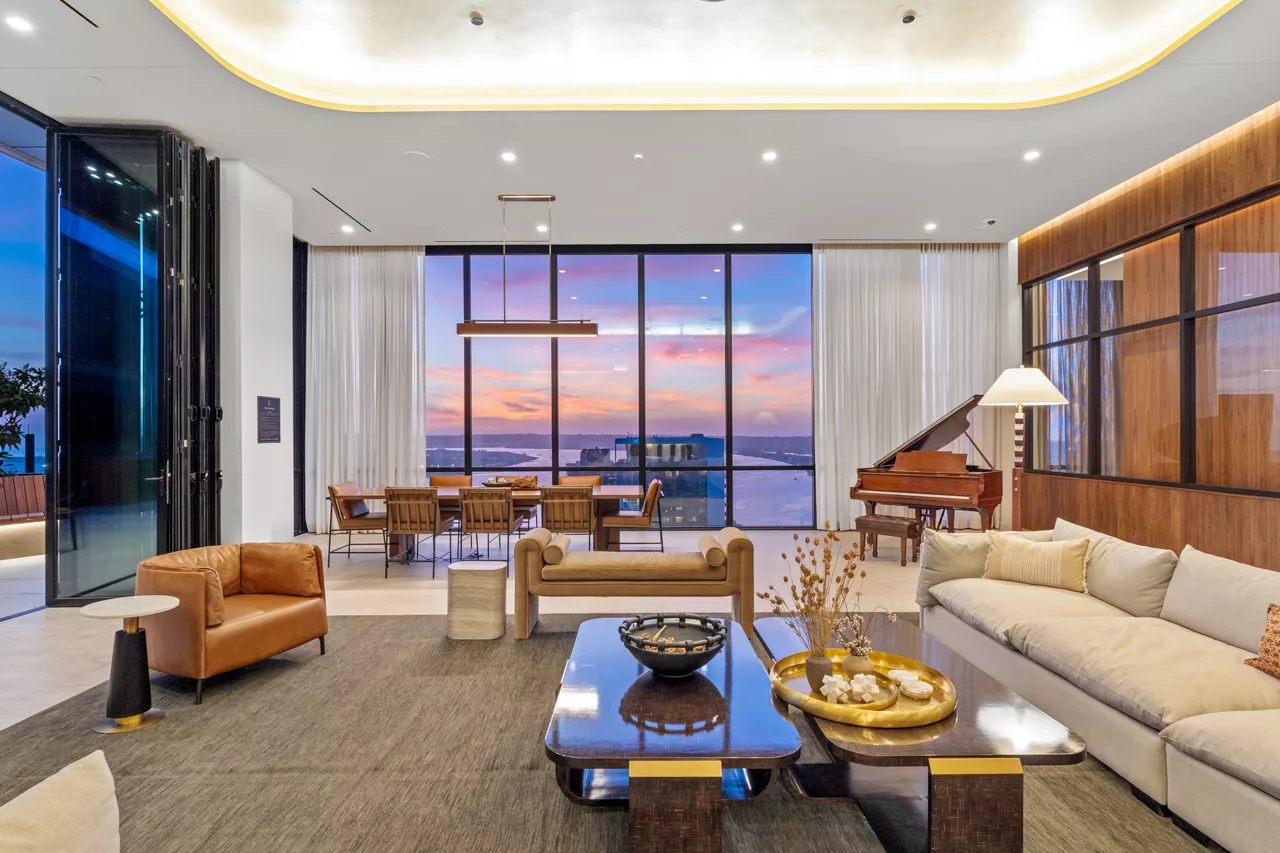 Modern sky lounge with panoramic sunset views, piano, sofas, and dining area.